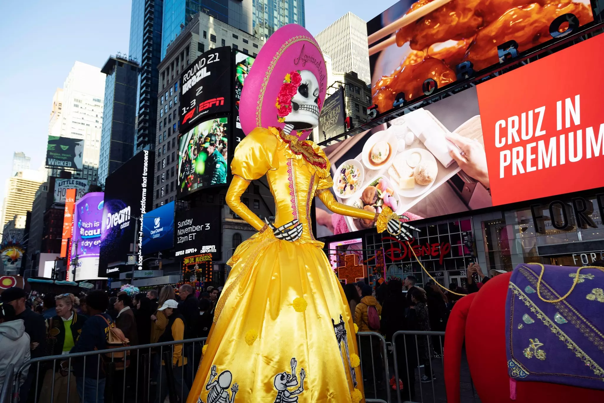 A catrina, or skeleton statue, in a yellow dress and pink sombrero in New York's Times Square