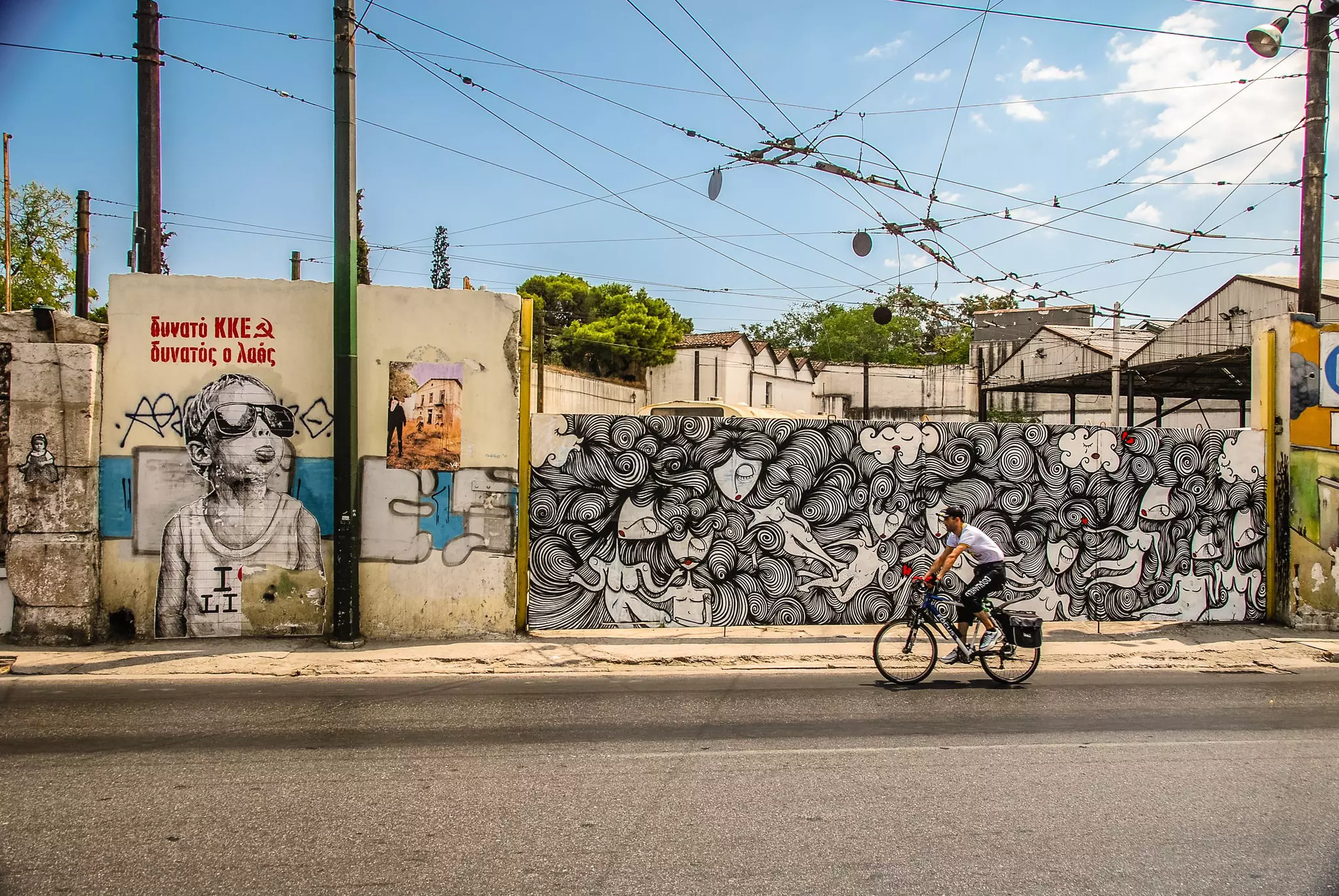 Man riding his bike past colourful graffiti in central Athens.
