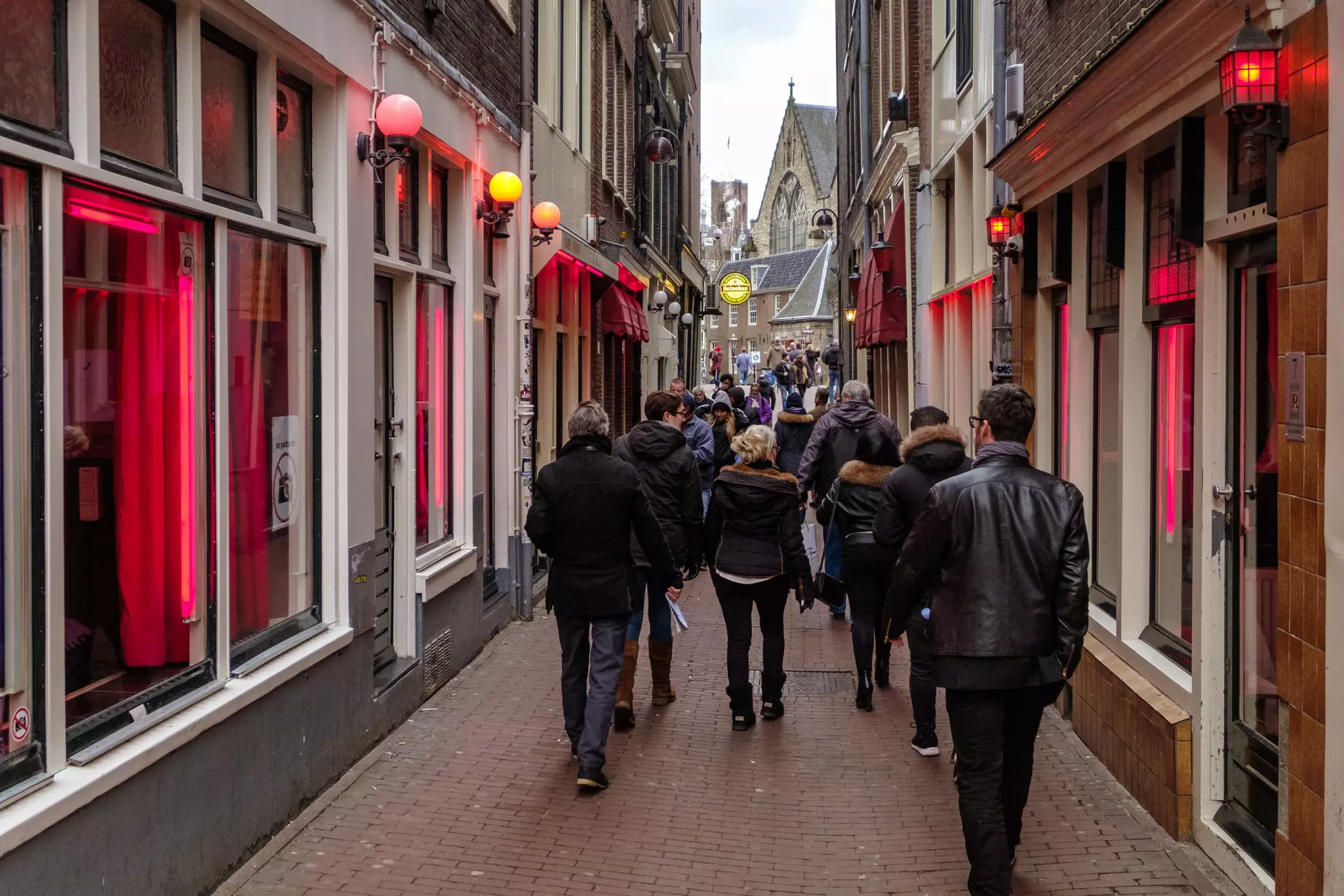 Tourists walking in the red light districts, where prostitutes try to lure customers from behind their windows.