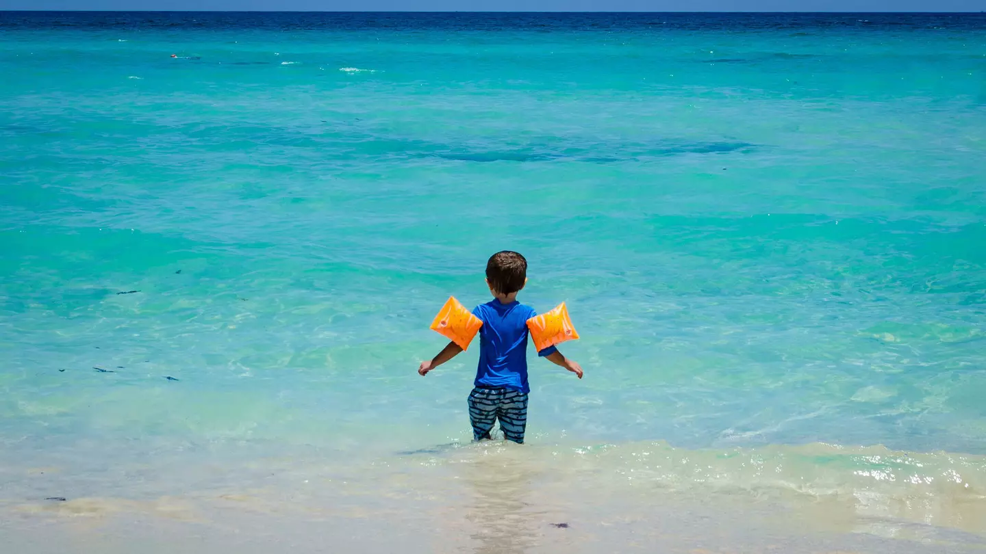 Young child wearing floaties at a Cuban beach.