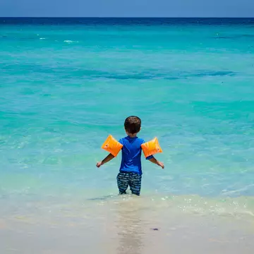 Young child wearing floaties at a Cuban beach.