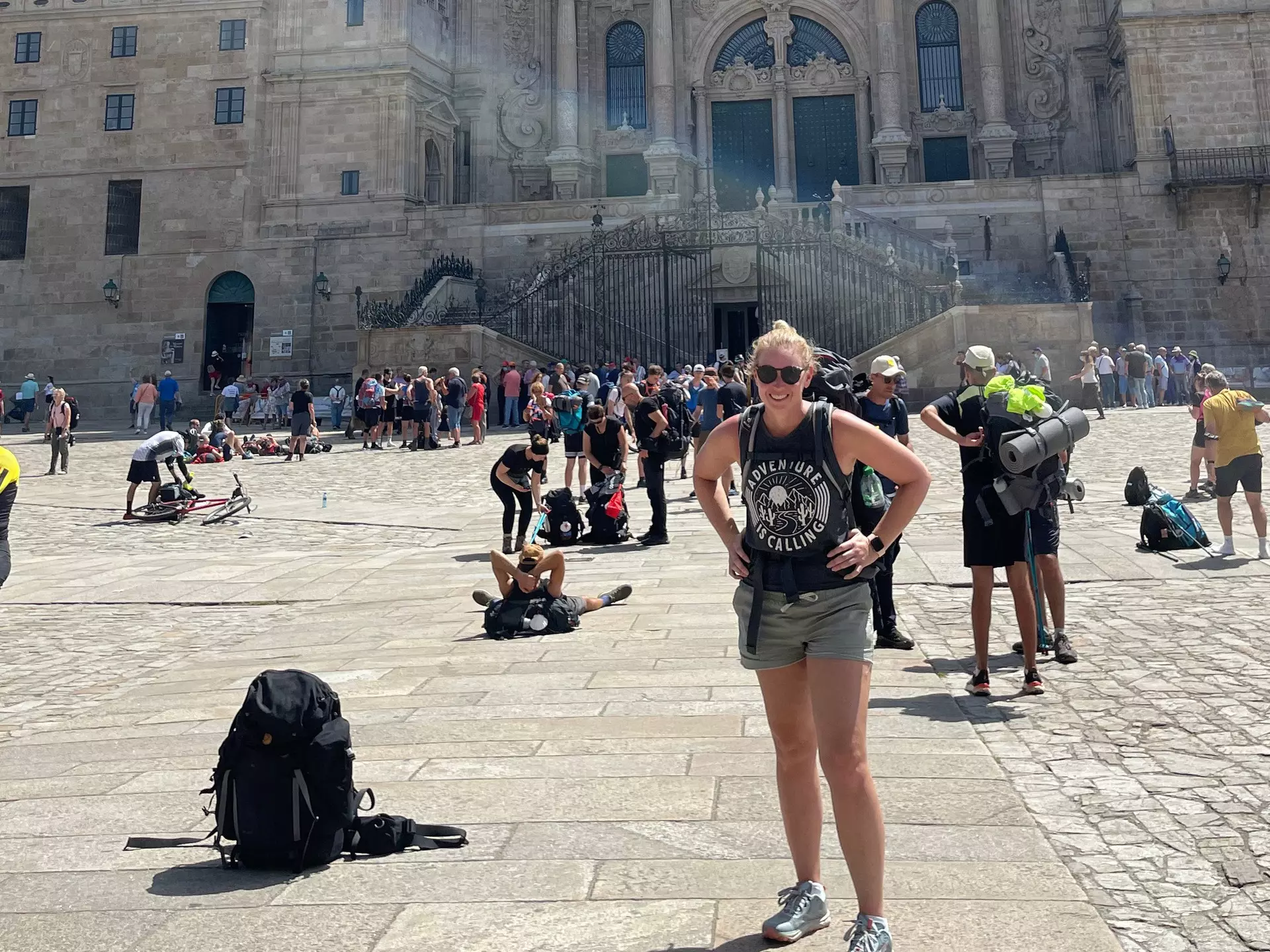 Woman with backpack in the sunshine outside a busy Spanish church