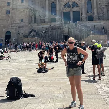 Woman with backpack in the sunshine outside a busy Spanish church