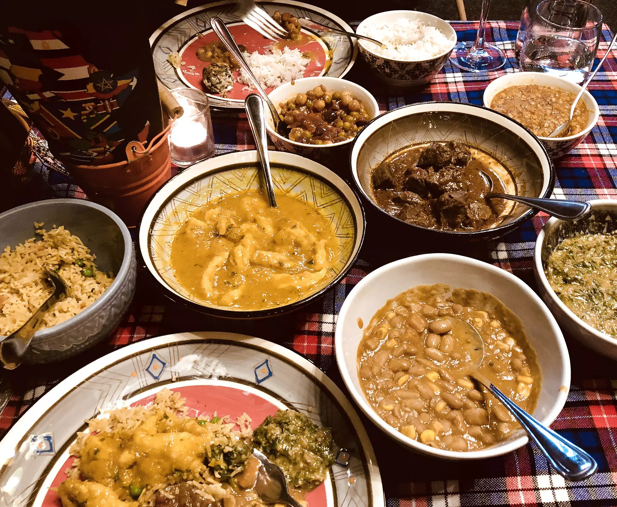 A table with bowls of various foods such as meats, beans and rice
