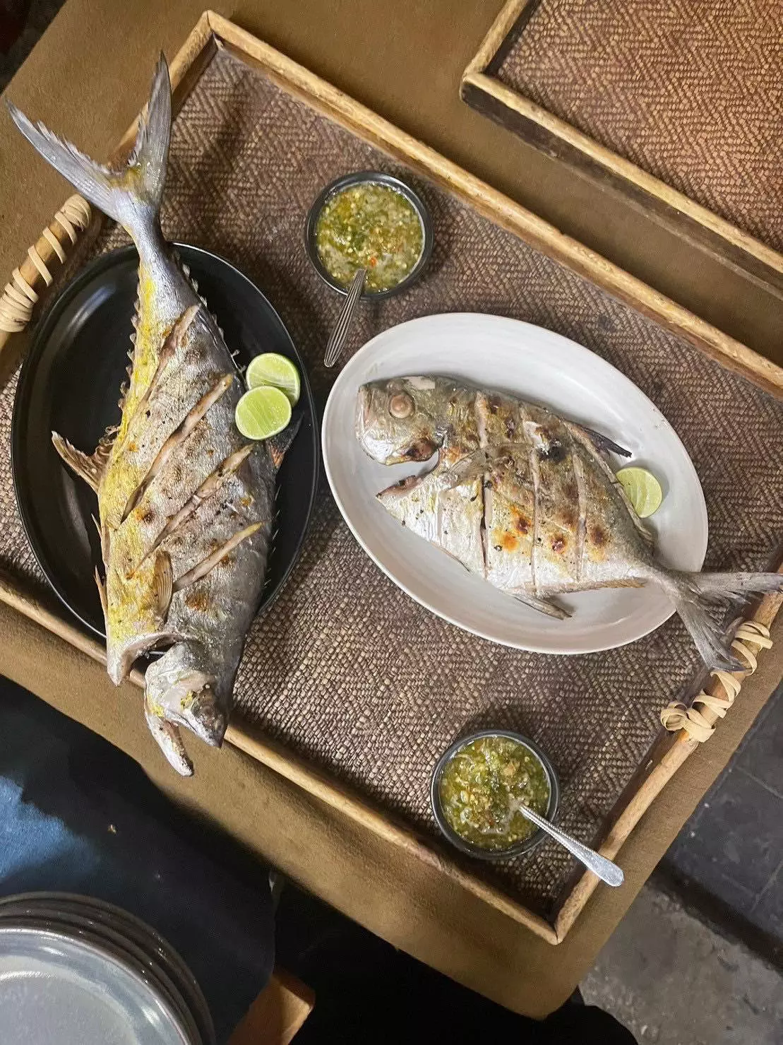 Cooked fish with fins on garnished plates on a wooden table