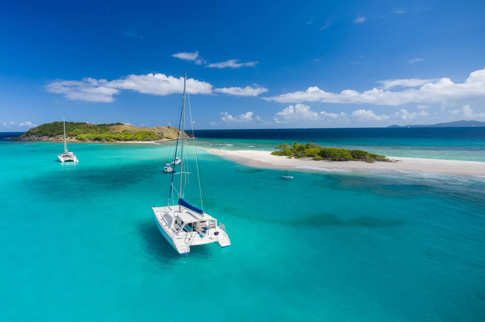 A catamaran moored near a tiny sandy island