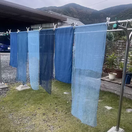 Pieces of fabric dyed blue hanging on a clothesline.