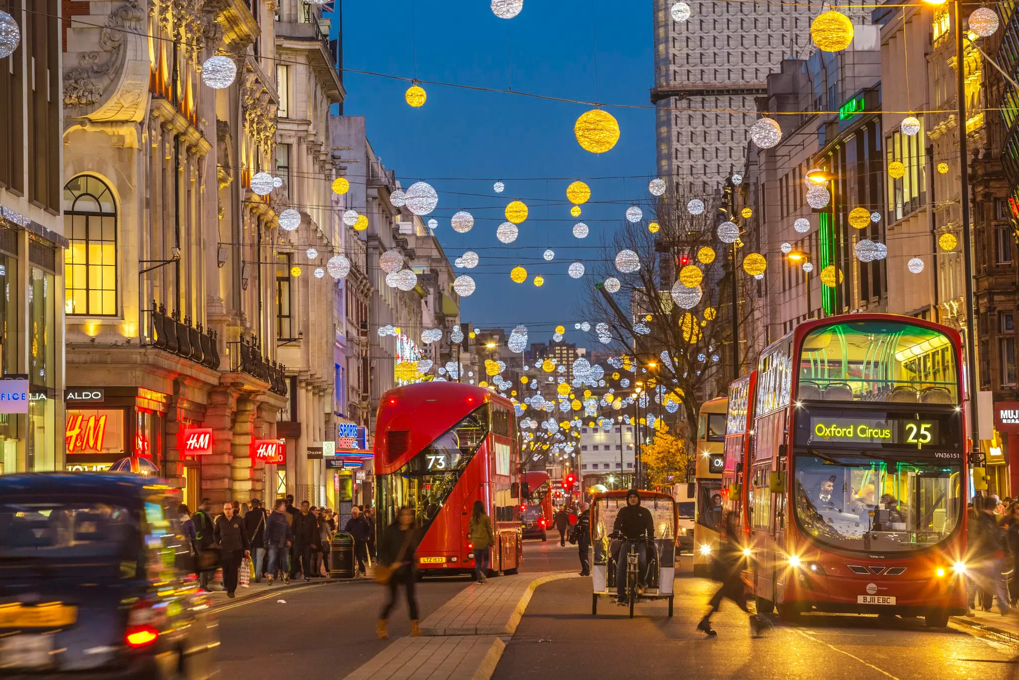 Buses pass under Christmas decorations in winter in Oxford Street, West End of London