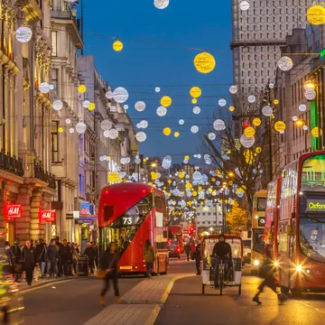 Buses pass under Christmas decorations in winter in Oxford Street, West End of London