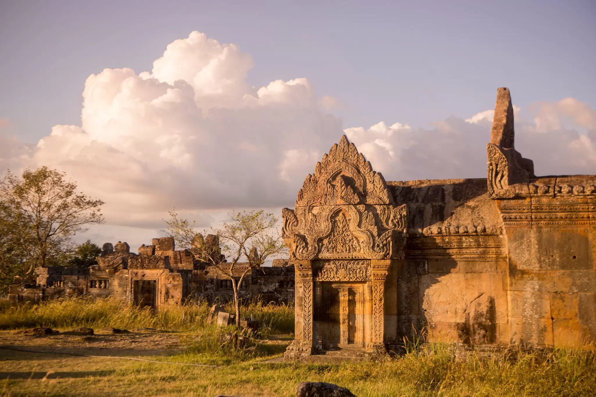 stone religious buildings in a field at sunset with white clouds above
