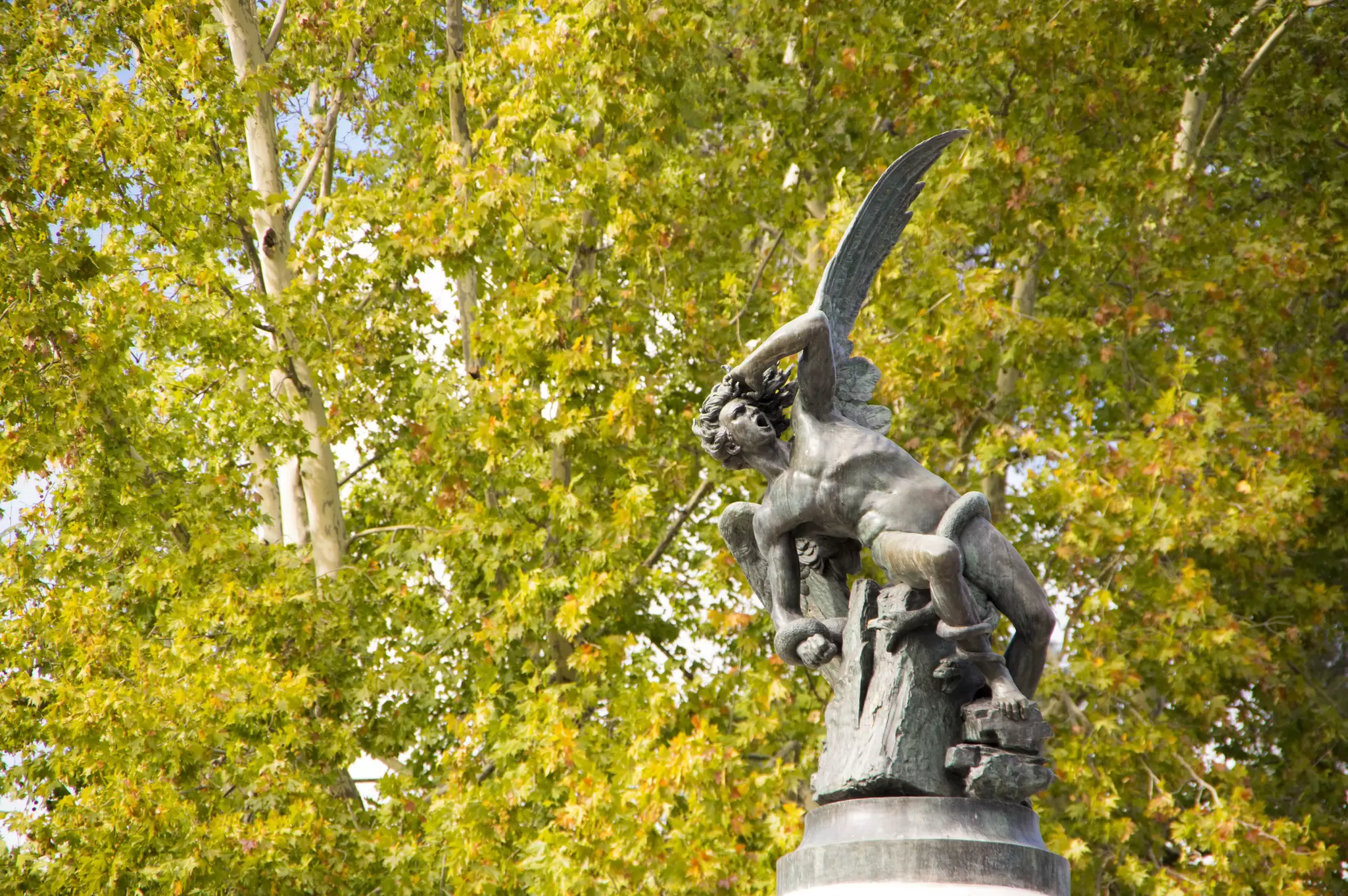 A statue of an angel in distress as demons surround it