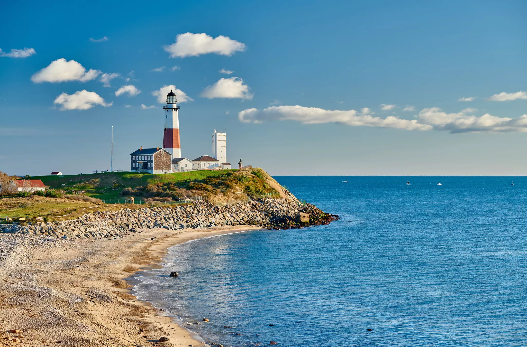A red and white lighthouse stands tall at a point of land that juts out into the sea.
