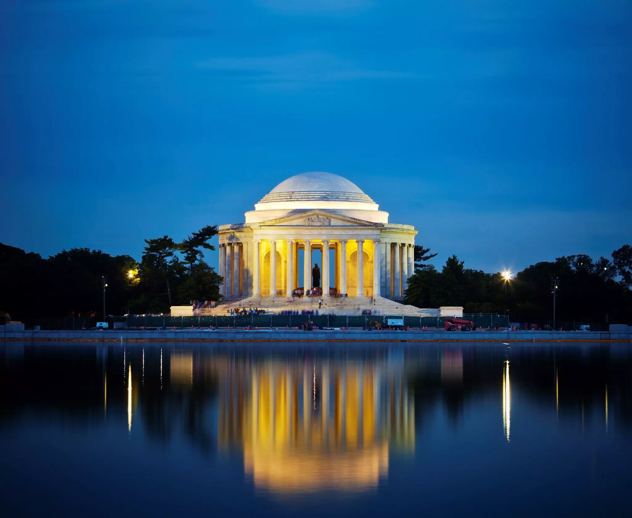 The Jefferson Memorial at night. The white-domed structure is reflected in the waters of the lake in front of it.