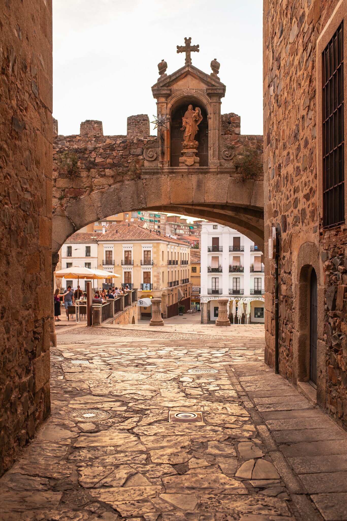 View of Plaza Mayor through the Arco de la Estrella during sunset in Cáceres, Spain.
