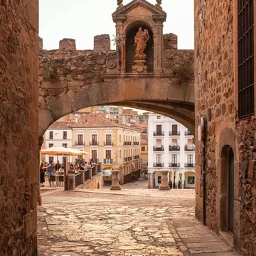View of Plaza Mayor through the Arco de la Estrella during sunset in Cáceres, Spain.