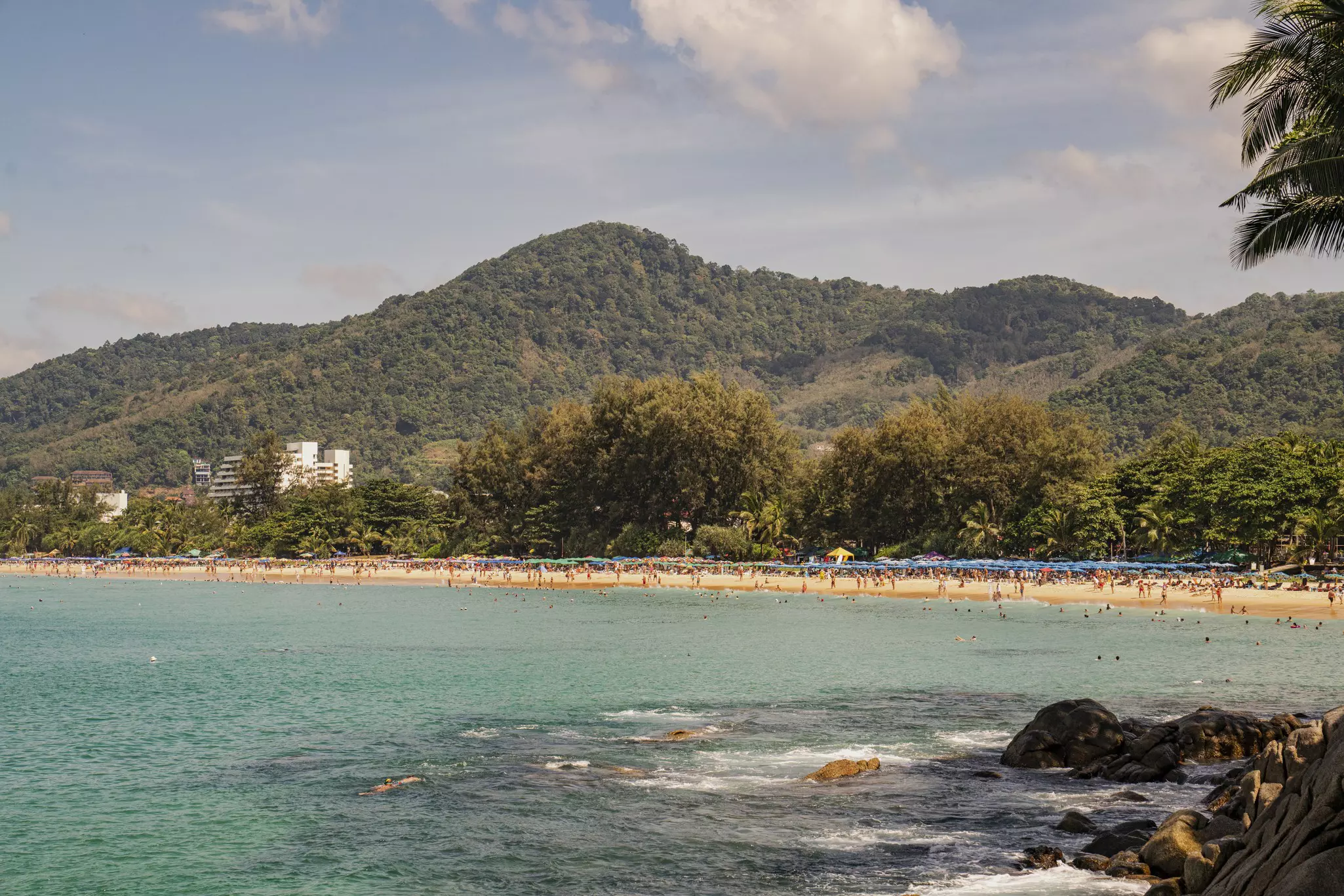 A view of a crowded beach with mountains in the back.
