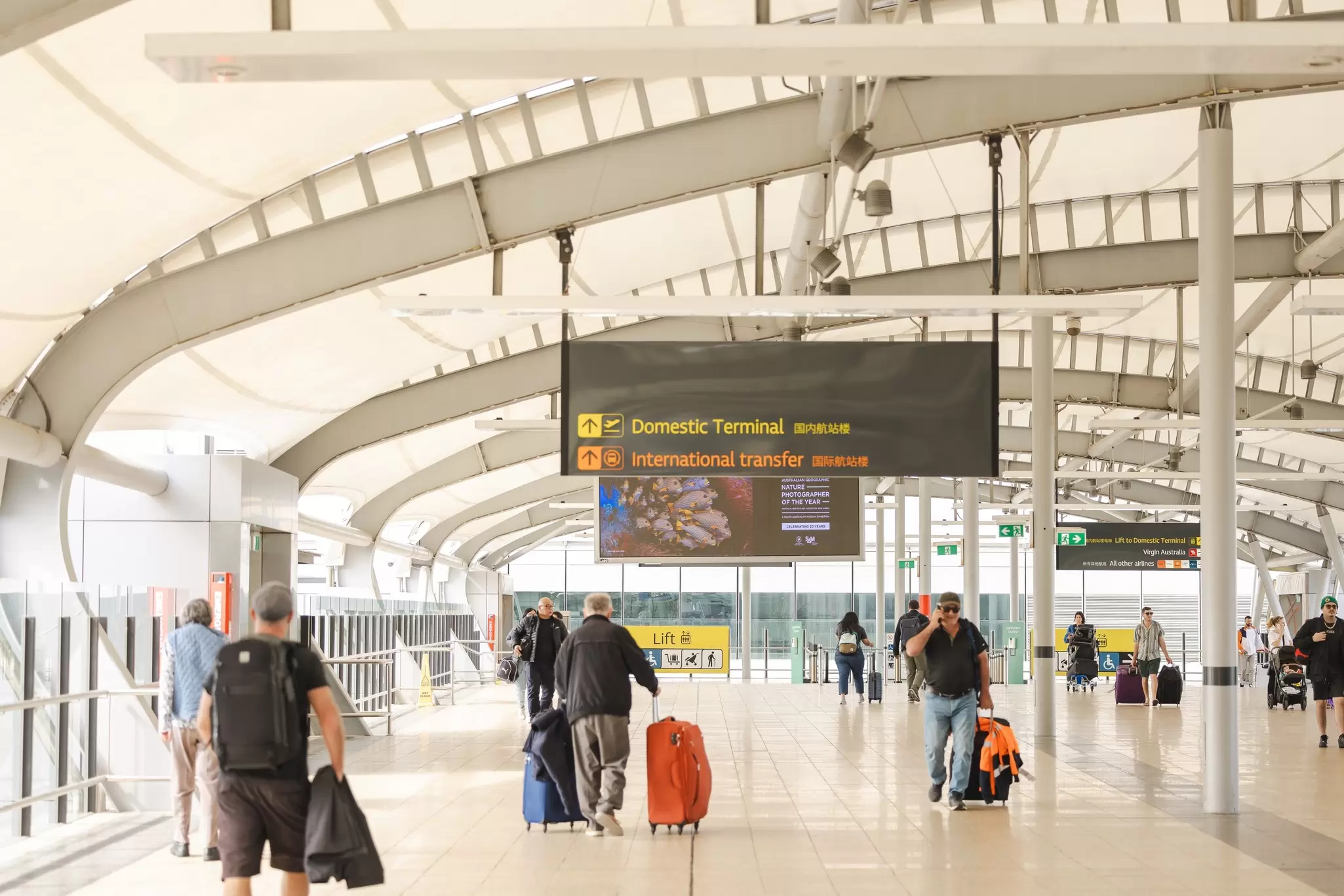 People wheel their bags through an airport concourse, Brisbane, Australia