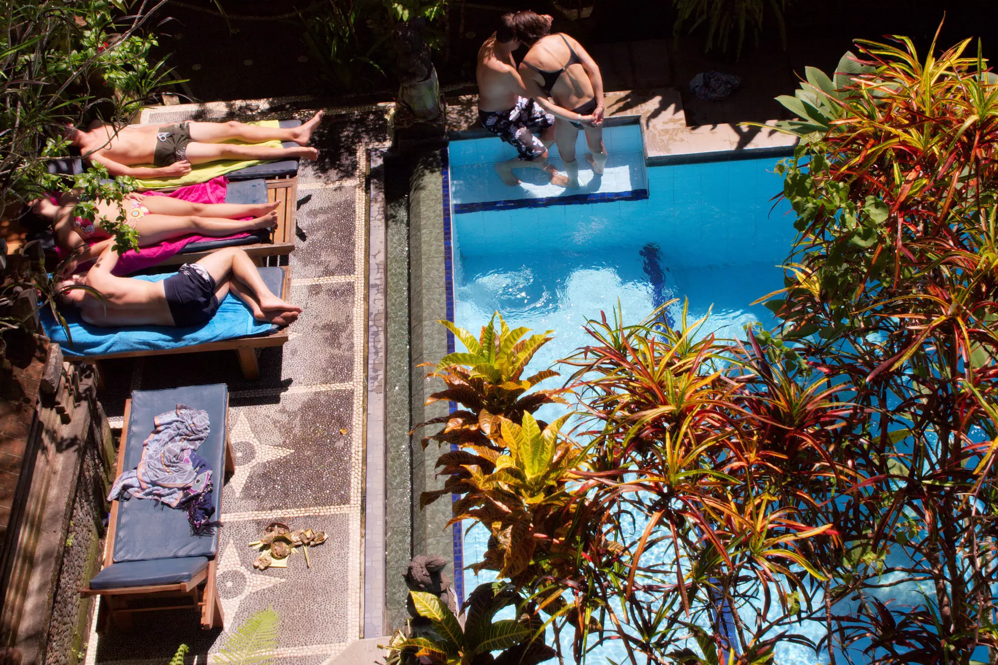 People relax around a swimming pool at a guesthouse in Bali, Indonesia.