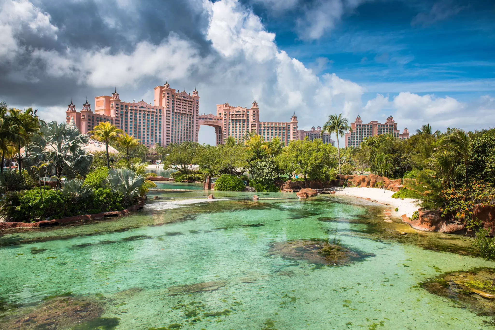 A cove with a small beach. The towers of a huge resort are seen in the background.