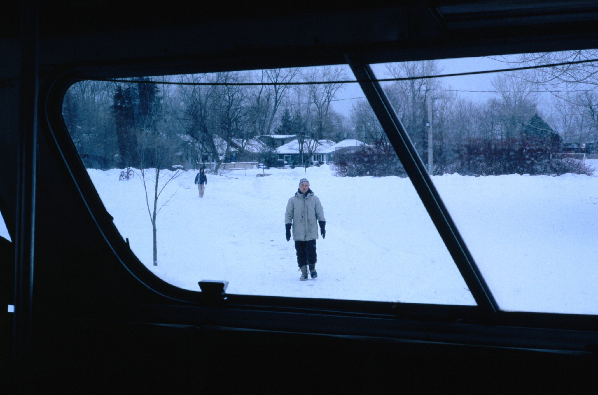 Person walking towards a bus on snowy Ward's Island in Toronto, Canada.