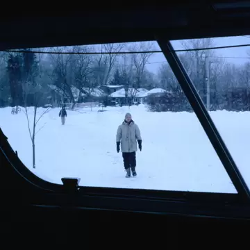 Person walking towards a bus on snowy Ward's Island in Toronto, Canada.