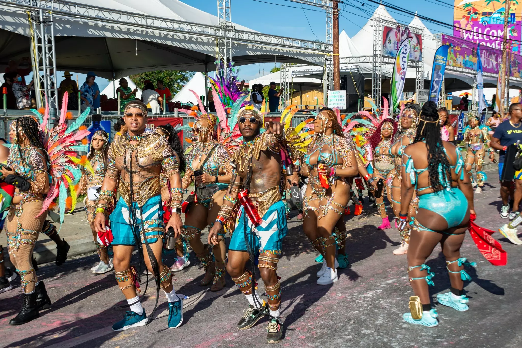 Dancers in elaborate costumes with beads and feathers parade down a street.