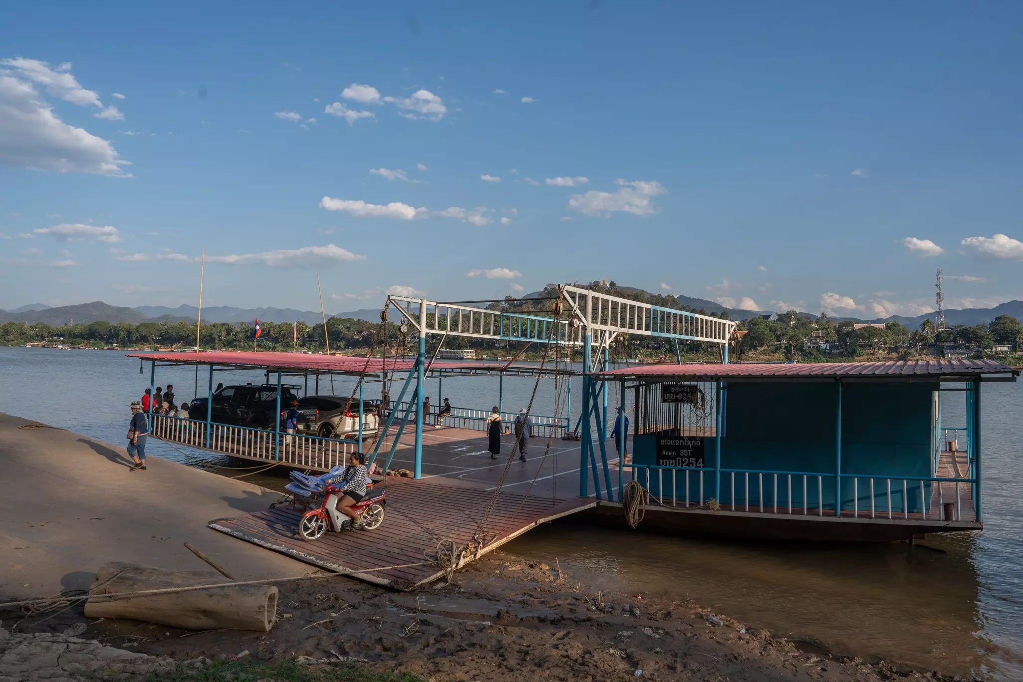 A Laotian ferry boat carries motorcycles, scooters, assorted vehicles and passengers from one bank of the Mekong River to the other