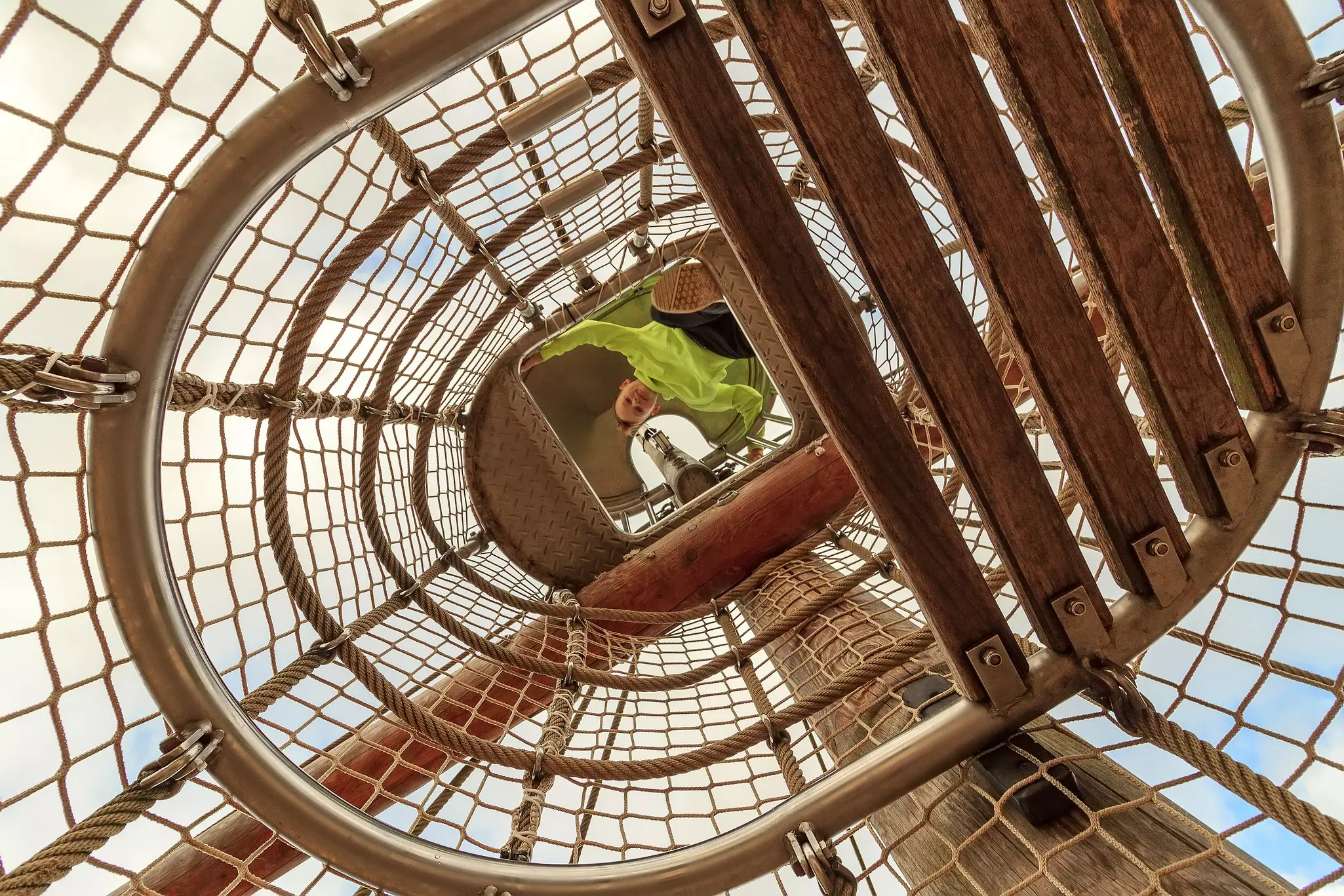 Boy playing inside the netting of a playground pirate ship