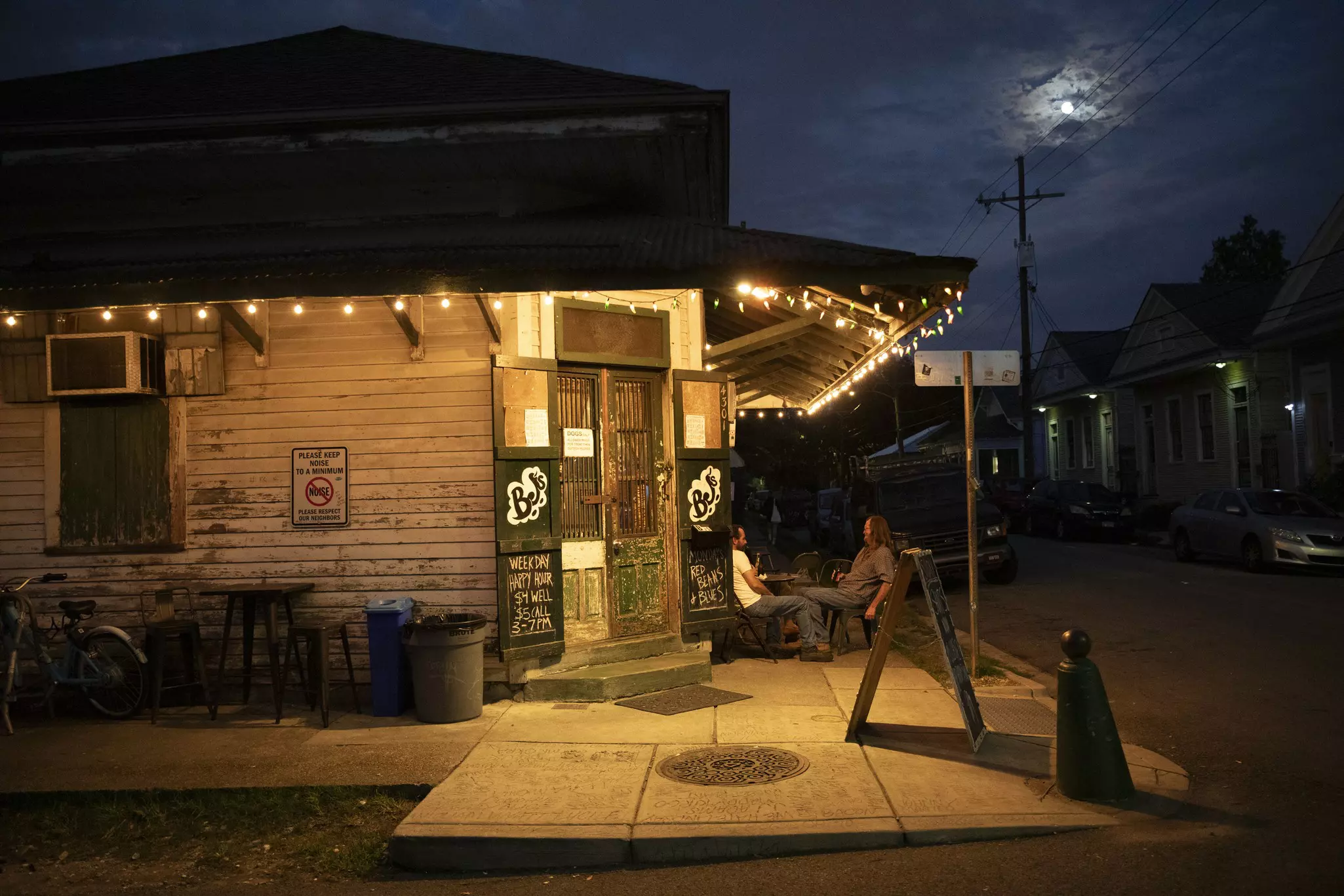 Two people sit outside a bar in the evening, Bywater, New Orleans