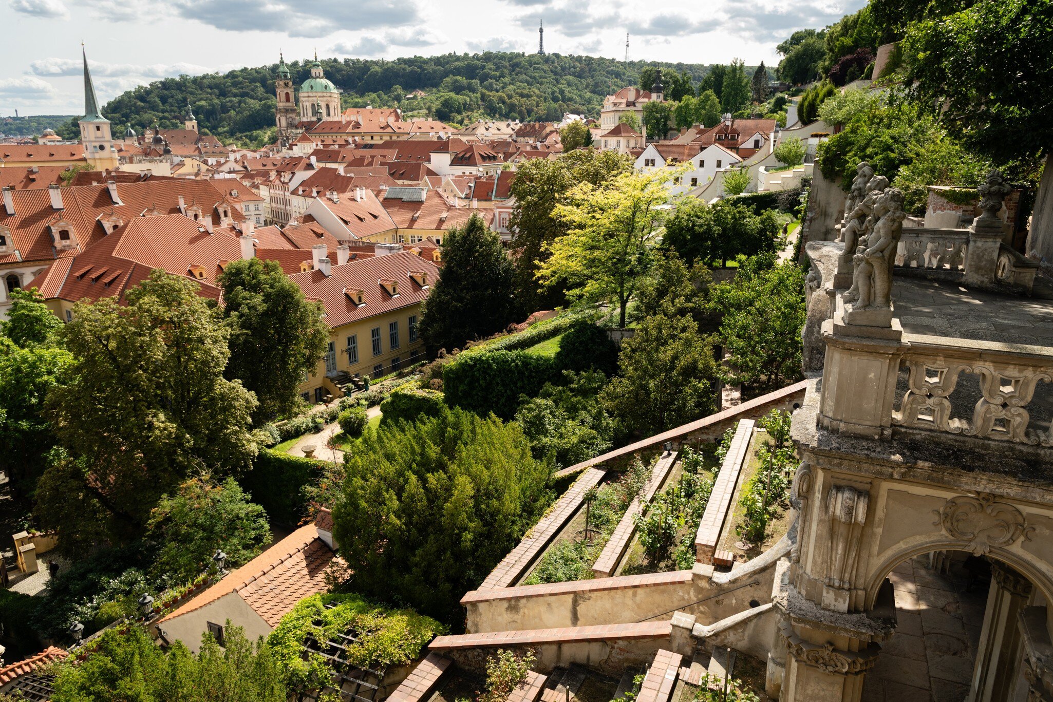 Prague, Czech Republic. View over the Palace Gardens below Prague Castle towards the dome of St Nicholas Church and Petřín with the lookout tower, Prague, on a bright summer afternoon.