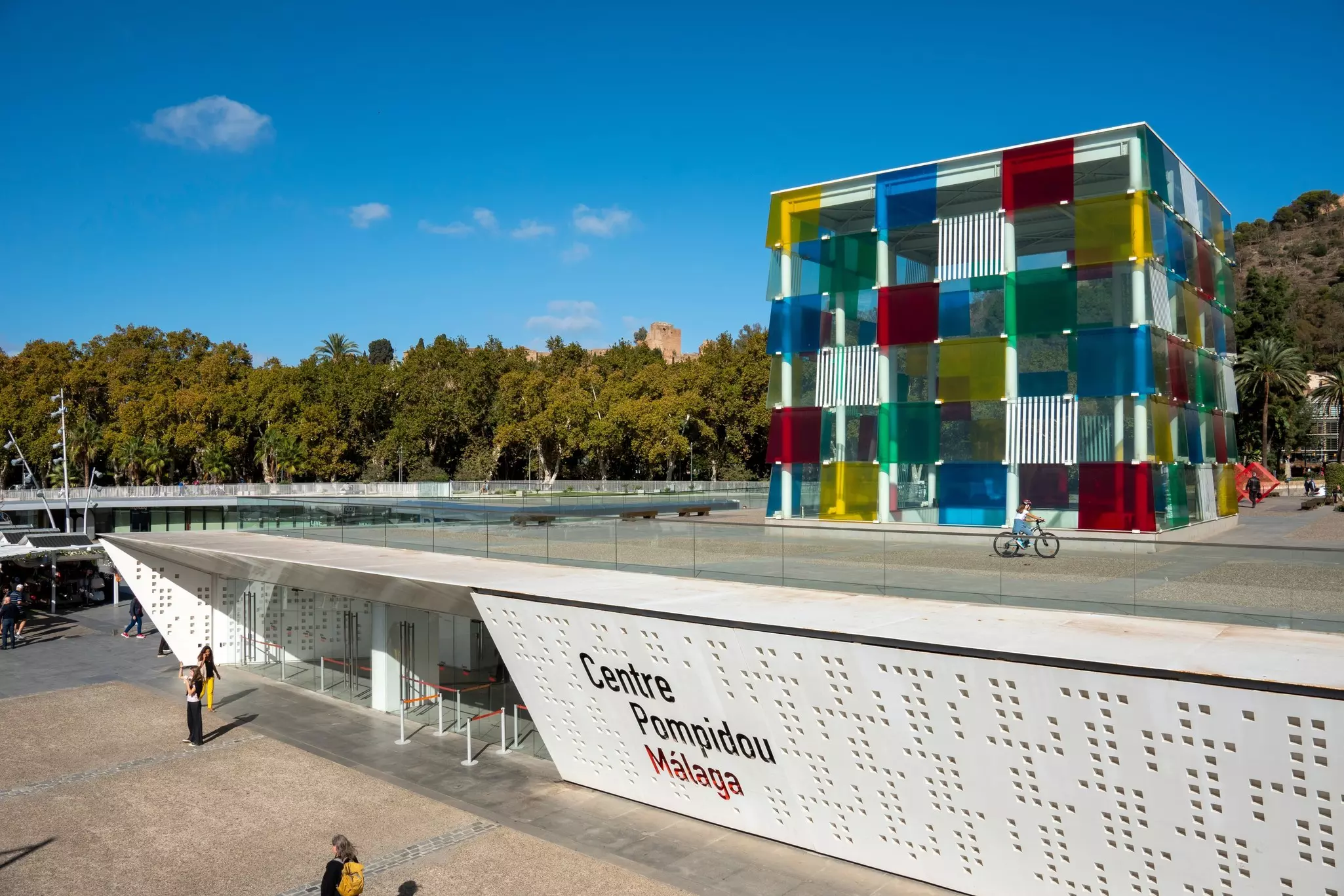 A white low-profile bulding with a colorful cube on its roof.