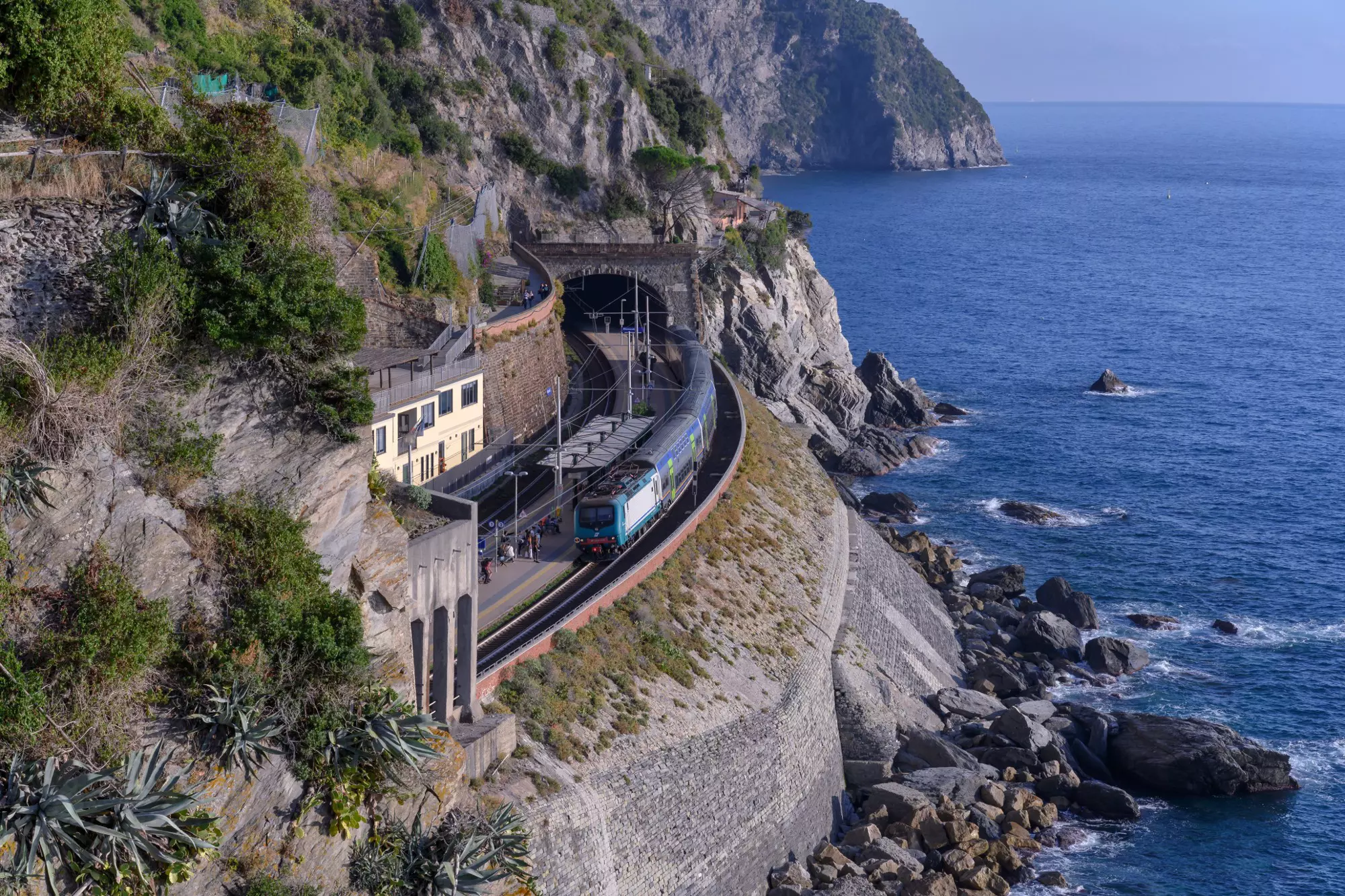 A train hugs the coast of Manarola, Italy