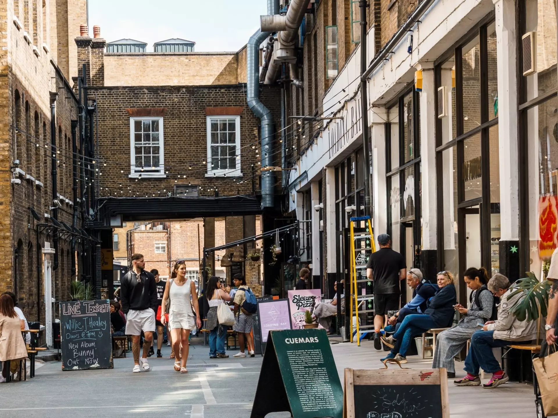 Street scene with people shopping in Dray Walk, a pedestrian street near Brick Lane in Shoreditch in London's East End.