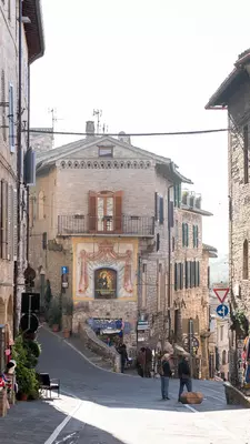 A streetscape in Assisi. Stone buildings line a cobblestone lane.