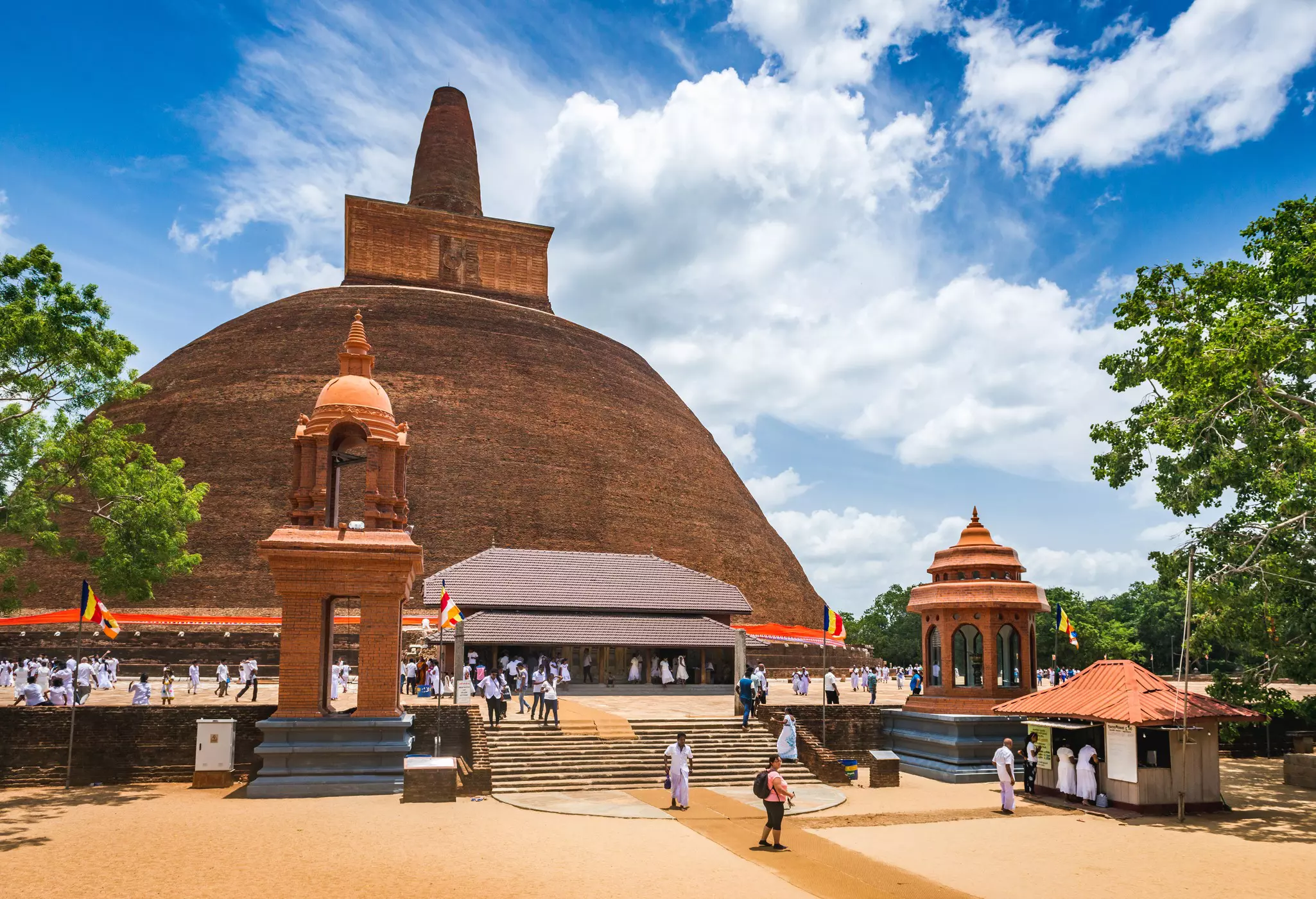 A vast brick stupa surrounded by pilgrims dressed in white.