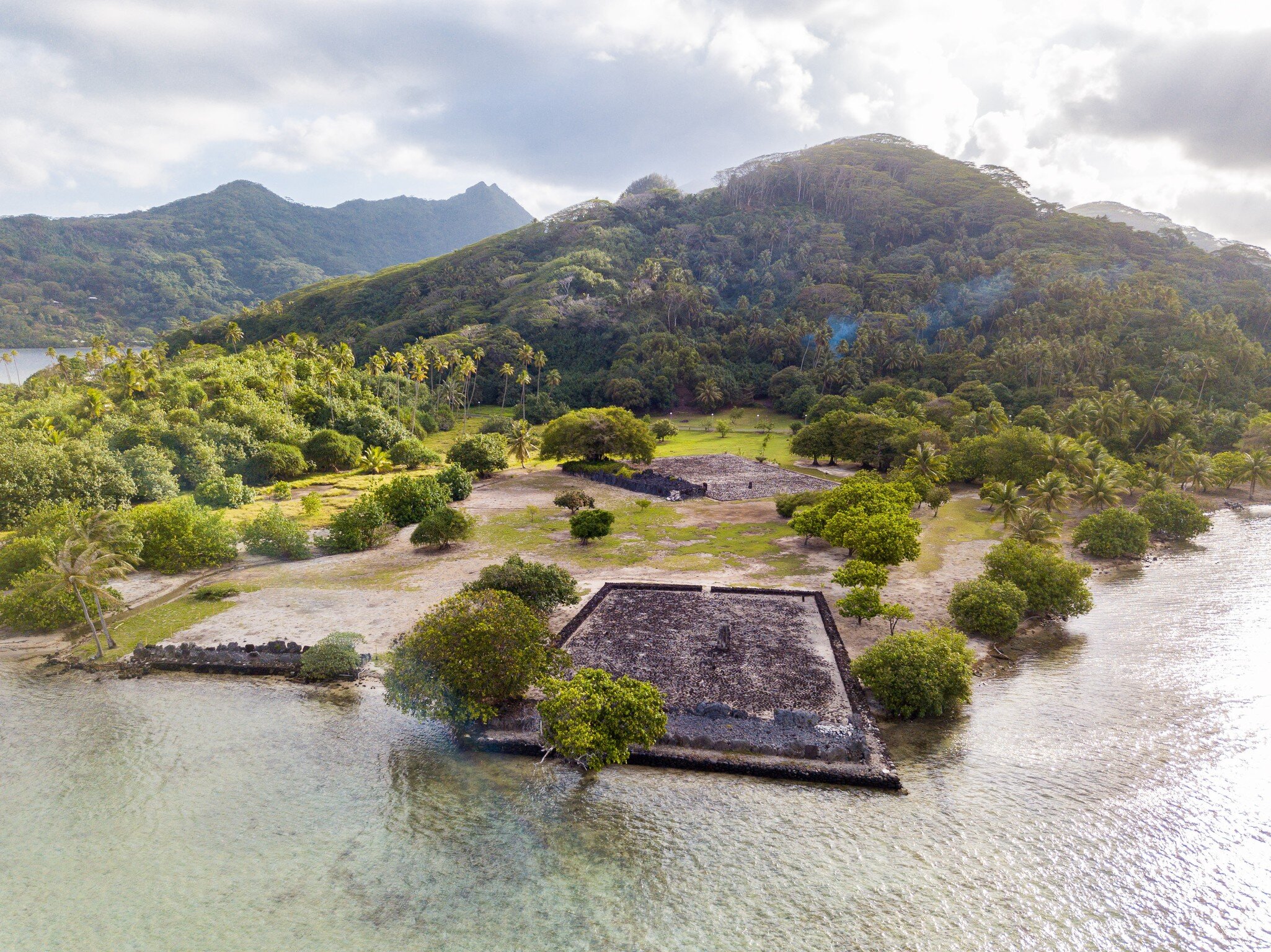 Ancient Marae Taputapuatea temple complex on the lagoon shore with mountains on background. Raiatea island. Leeward / Society Islands, French Polynesia, Oceania, South Pacific Ocean. Aerial view., License Type: media, Download Time: 2025-04-16T20:31:31.000Z, User: carolfarrell170, Editorial: false, purchase_order: 56530 - Guidebooks, job: Global Publishing WIP, client: Tahiti & French Polynesia 12, other: carol farrell
