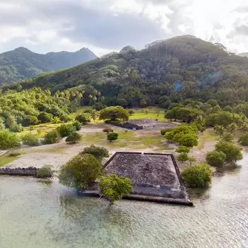 Ancient Marae Taputapuatea temple complex on the lagoon shore with mountains on background. Raiatea island. Leeward / Society Islands, French Polynesia, Oceania, South Pacific Ocean. Aerial view., License Type: media, Download Time: 2025-04-16T20:31:31.000Z, User: carolfarrell170, Editorial: false, purchase_order: 56530 - Guidebooks, job: Global Publishing WIP, client: Tahiti & French Polynesia 12, other: carol farrell