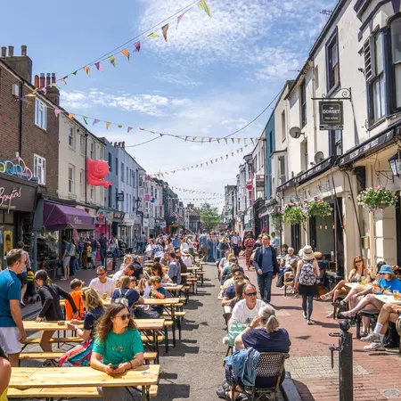 Brighton Gardener Street cafes and restaurants and bunting over the people dining in the sun, East Sussex  