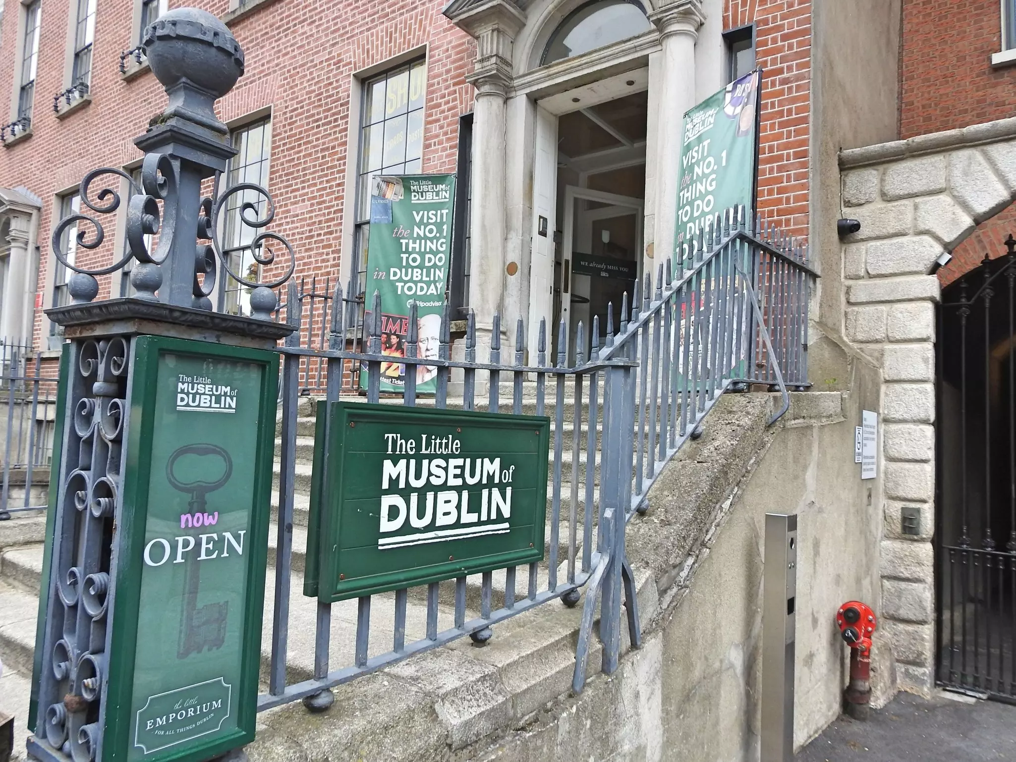 A set of steps lead up into a townhouse with a sign that reads "The Little Museum of Dublin"