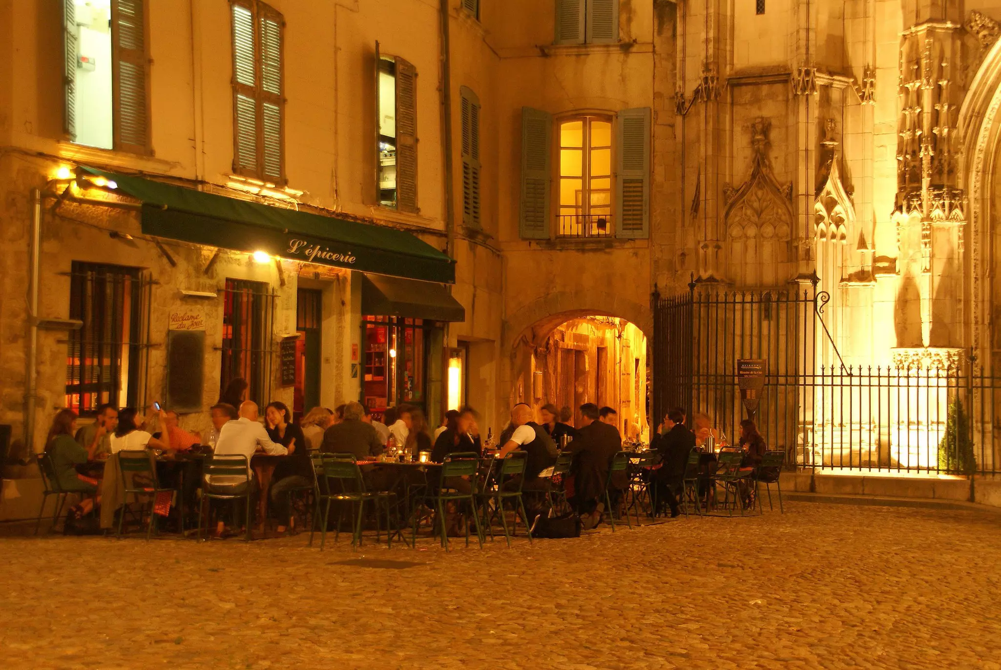 Casual diners enjoy an evening meal near an old church in Avignon, France