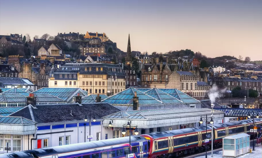 Stirling railway station with ScotRail trains and glass canopies, Stirling Castle on the hill above, snow on the platform