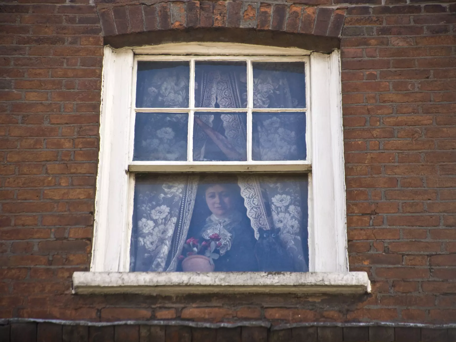 A woman is pictured in a trompe l'oeil window in London.