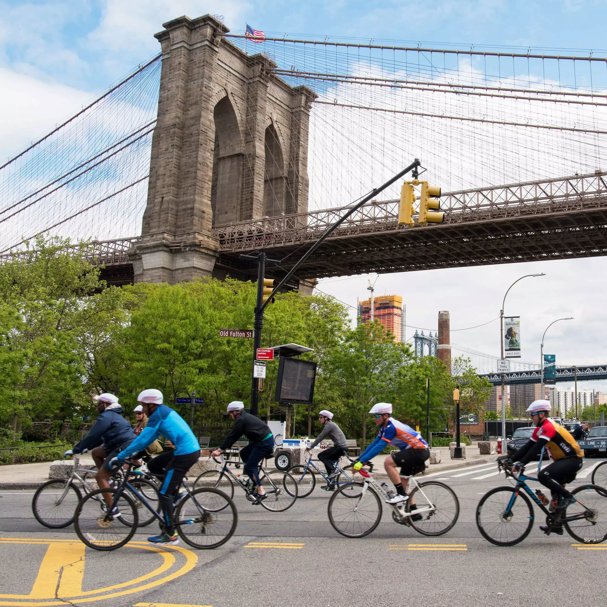 A cycle tour group passes the Brooklyn Bridge in New York City, USA.