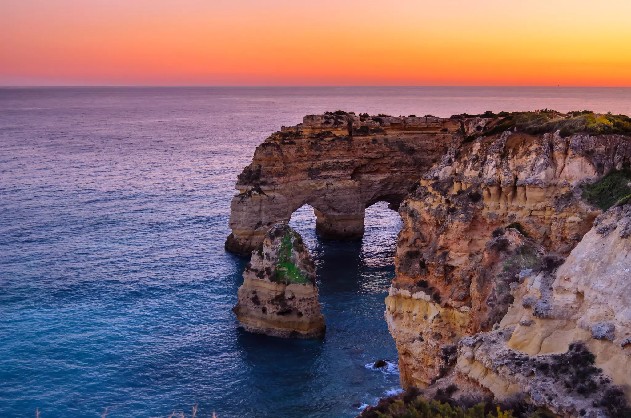 Two natural arches carved within rocky cliffs by the sea.