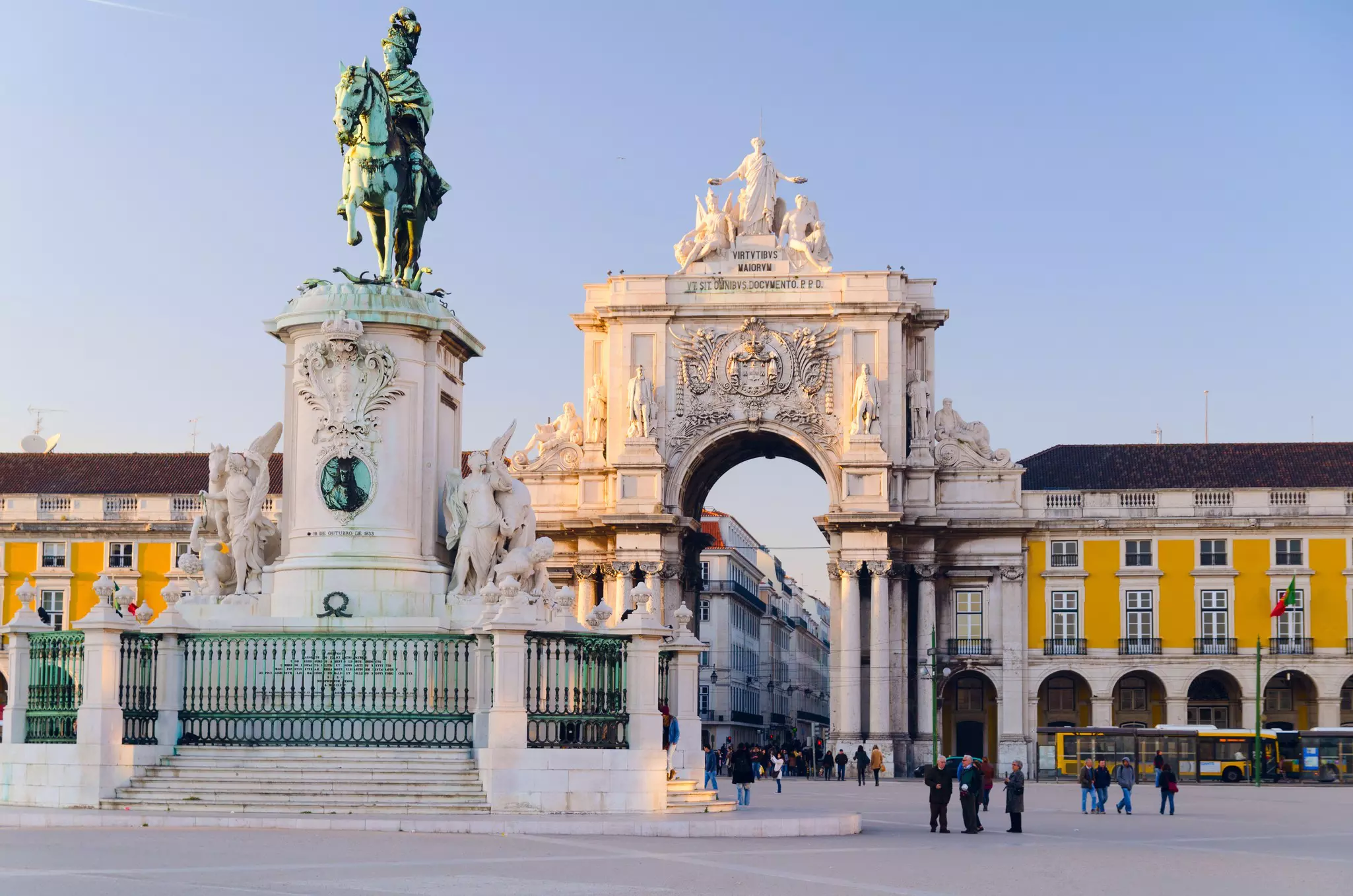 A large city square with a central statue of a man on horseback, backed by a large ornate archway. People walk by dressed in warm winter clothes.