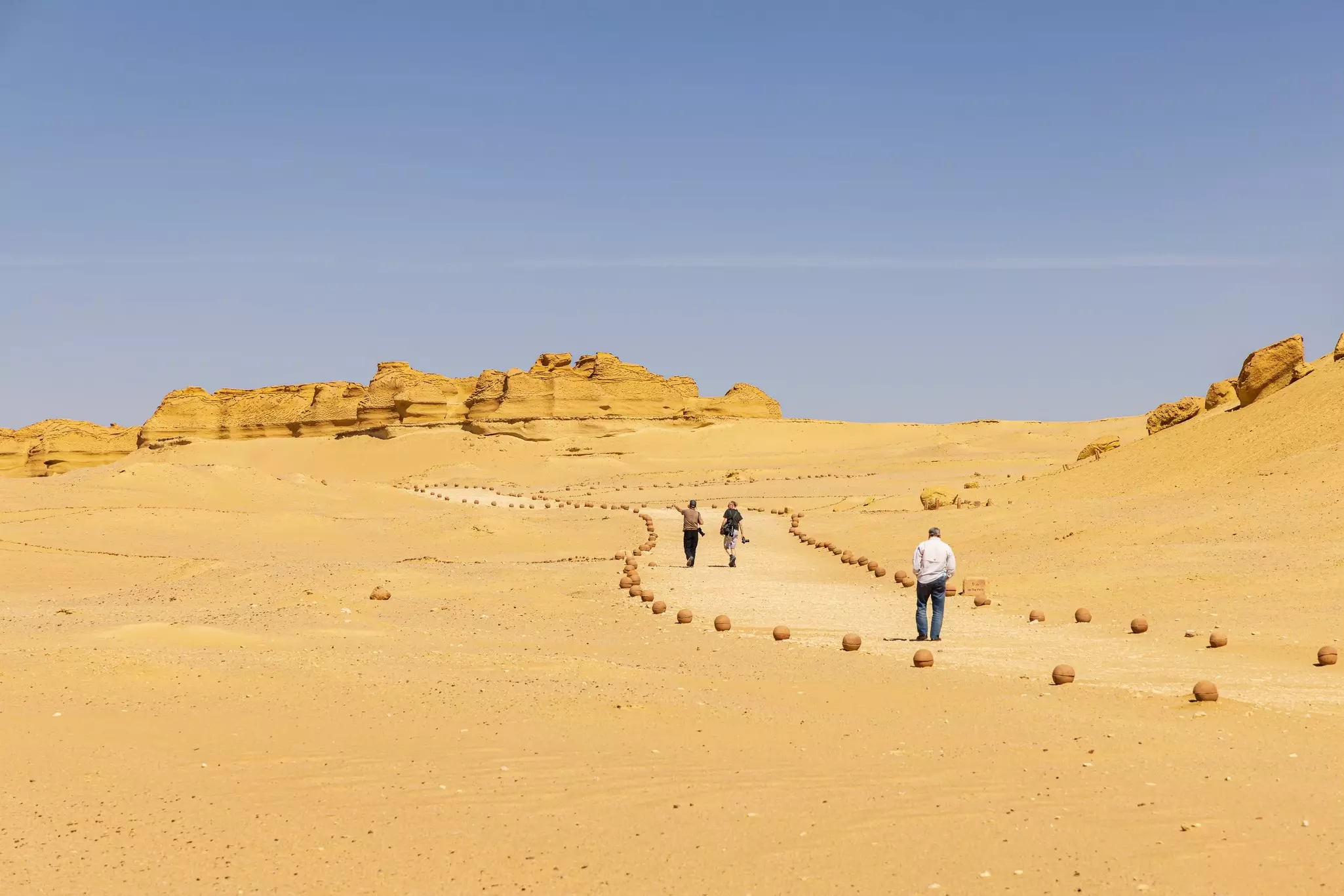 People follow a trail marked out by rocks in a desert landscape.