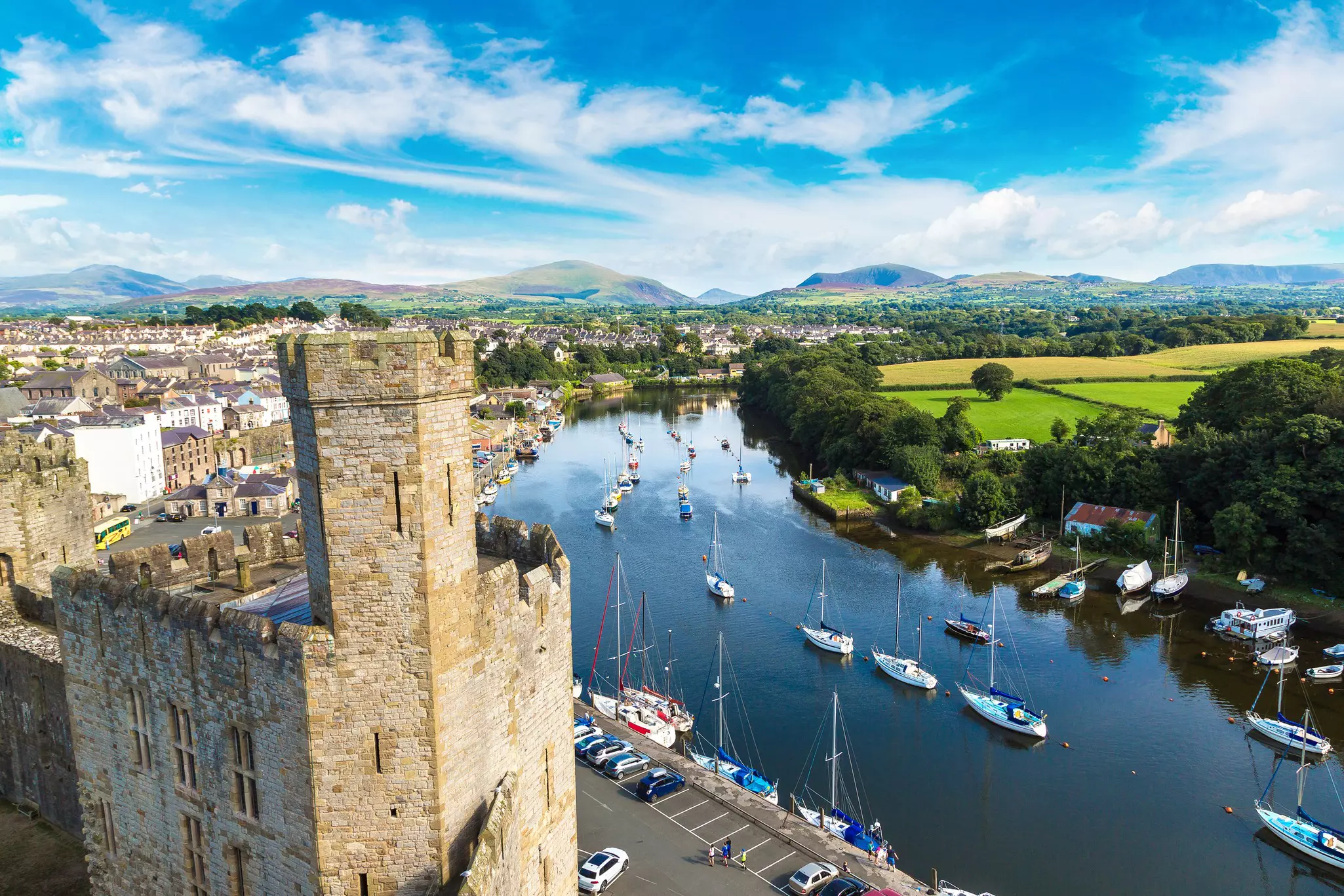 Caernarfon Castle in Wales in a bright summer day, with boats on the river.
