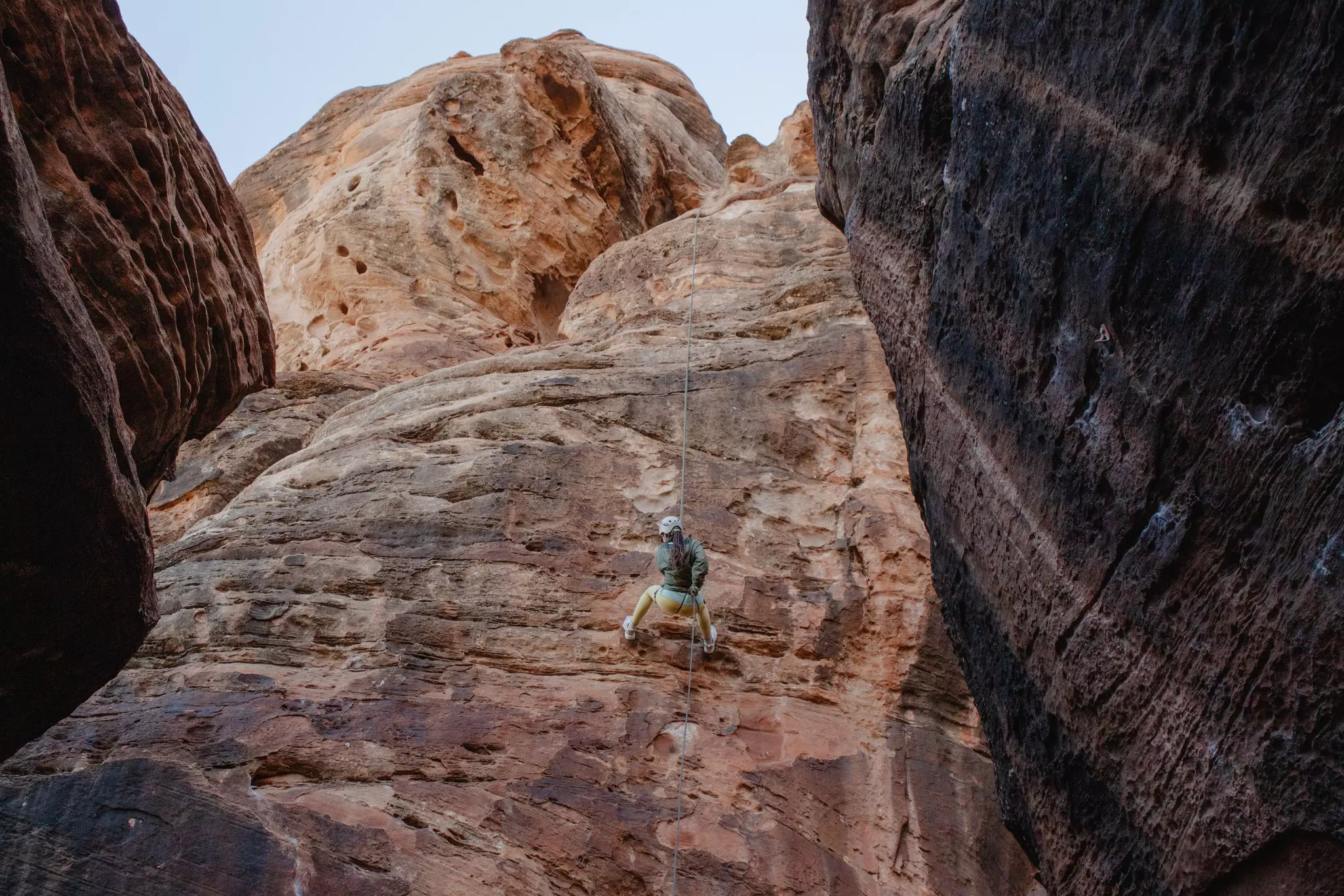 A woman rappels down a cliff.