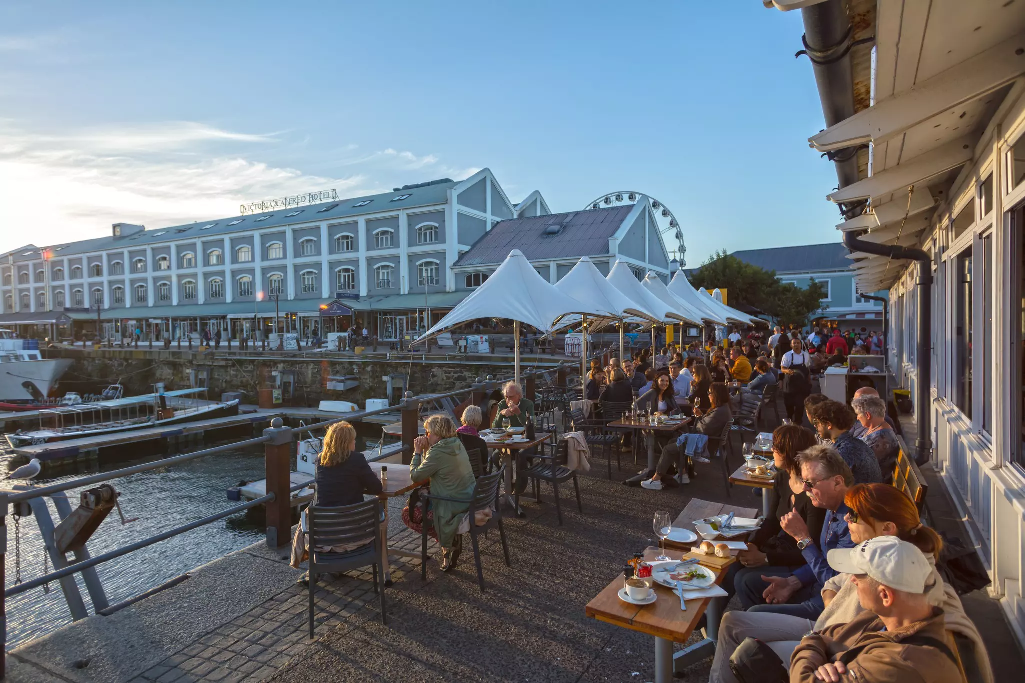 People enjoy sunset on a restaurant patio overlooking the waterfront in Cape Town