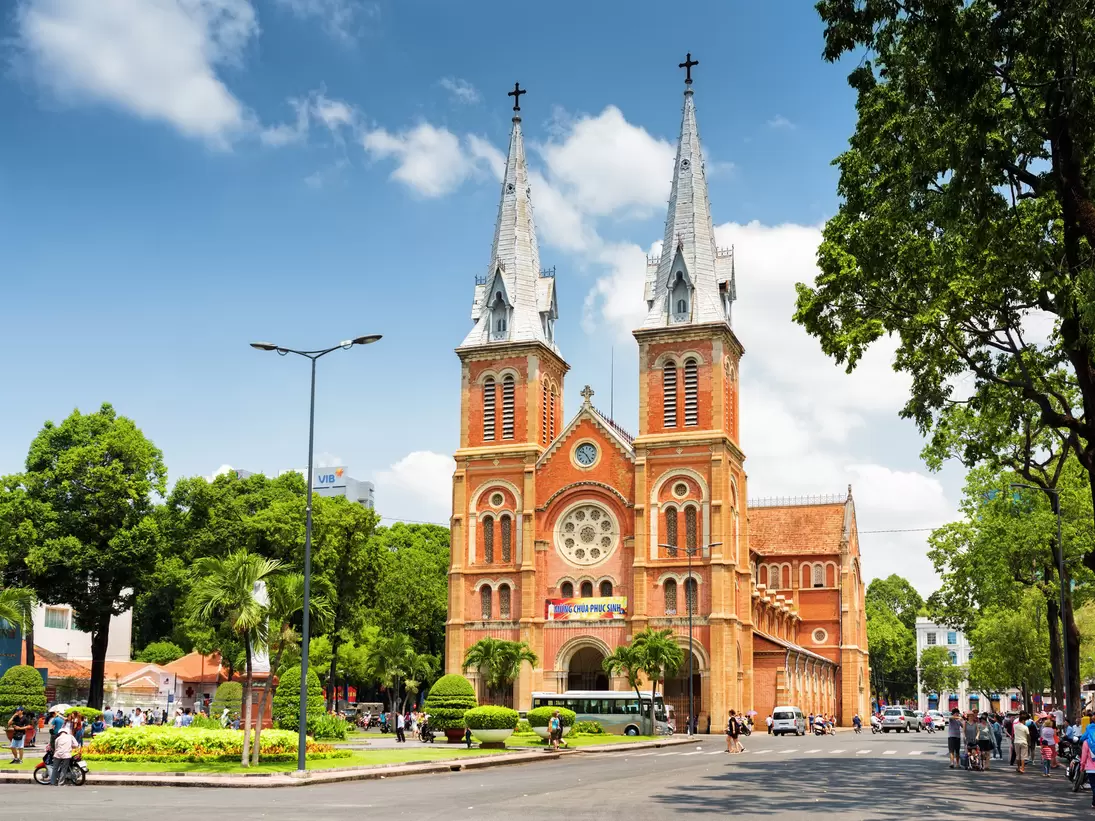 HCMC's Notre Dame Cathedral and the leafy surrounding square and street on a sunny, clear day